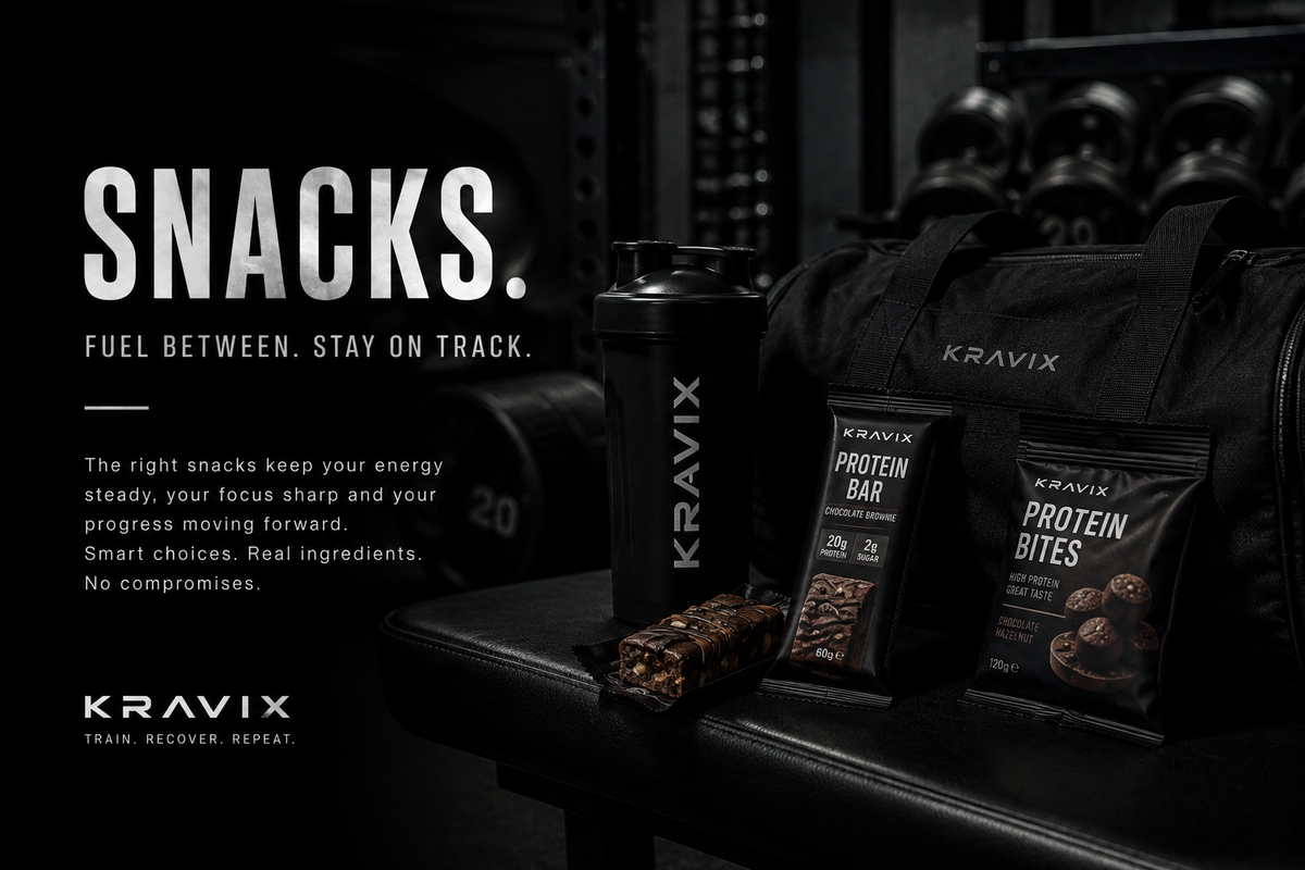 Kravix branded black shaker bottle, protein bar, and protein bites arranged on a black bench in a dark gym setting, with large white text reading 'SNACKS. FUEL BETWEEN.